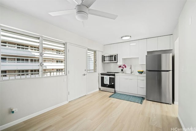 kitchen with light wood finished floors, white cabinets, modern cabinets, appliances with stainless steel finishes, and a sink