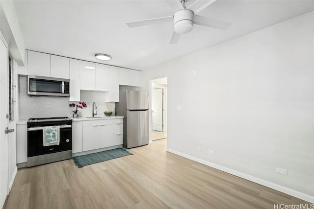 kitchen with stainless steel appliances, light wood-style flooring, a sink, and white cabinetry