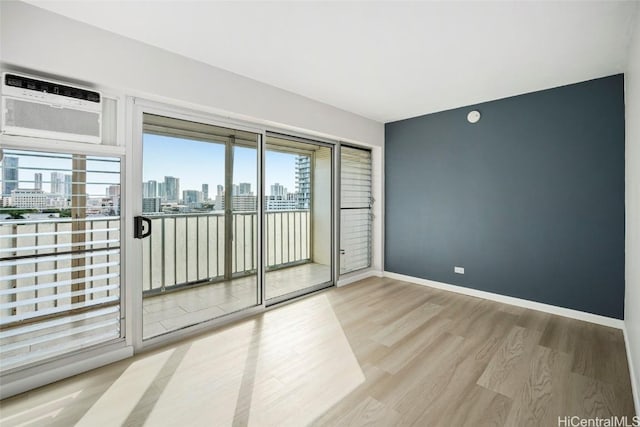 empty room featuring baseboards, a wall unit AC, wood finished floors, and a city view