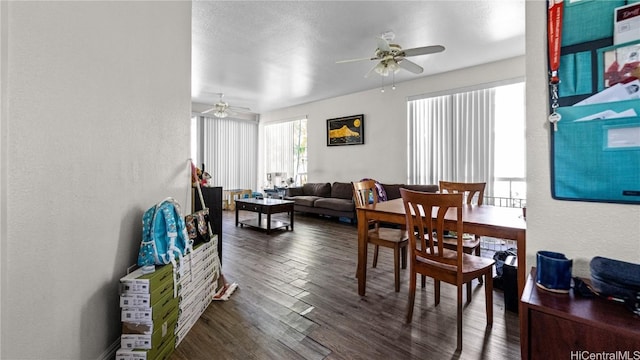 dining area featuring a textured wall, dark wood finished floors, and ceiling fan