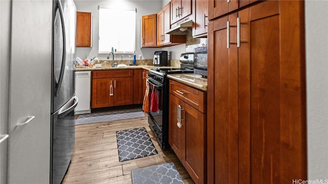 kitchen featuring under cabinet range hood, a sink, black range oven, freestanding refrigerator, and dishwasher