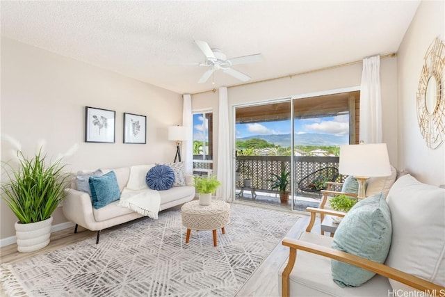 sitting room featuring ceiling fan, a textured ceiling, wood finished floors, and baseboards