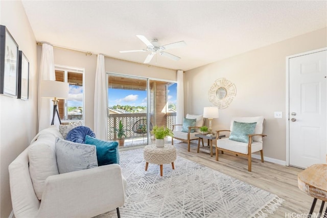 living area with wood finished floors, a ceiling fan, and baseboards