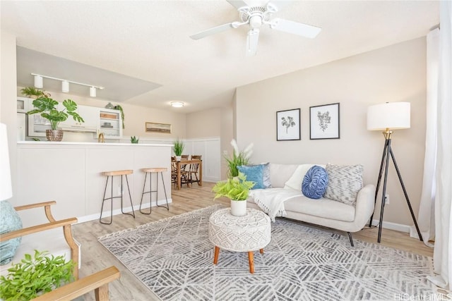 living area featuring light wood-style flooring and a ceiling fan