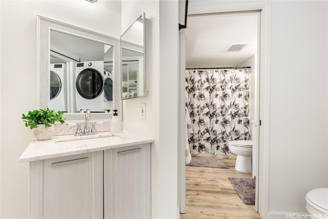 bathroom featuring visible vents, toilet, washing machine and dryer, vanity, and wood finished floors