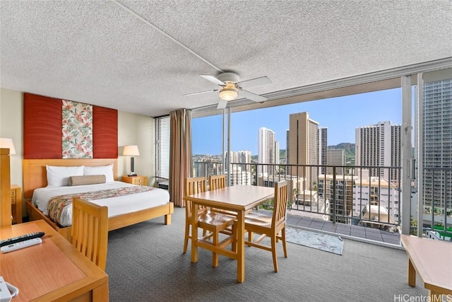 bedroom with a view of city, expansive windows, carpet flooring, and a textured ceiling