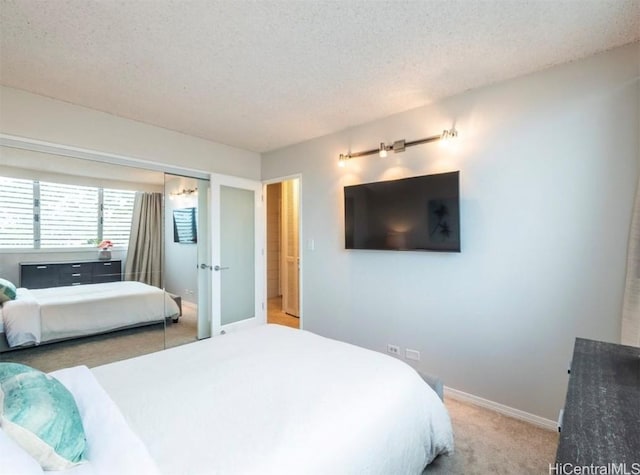 bedroom featuring light colored carpet, a textured ceiling, and baseboards