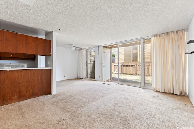 94-414 Kapuahi St Unit 23, Honolulu, HI 96789 - unfurnished living room featuring a textured ceiling, carpet, a wall of windows, and ceiling fan