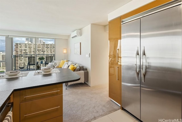 kitchen with light tile patterned floors, a wall unit AC, light carpet, open floor plan, and stainless steel built in fridge