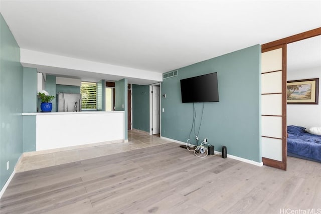 unfurnished living room featuring visible vents, baseboards, and wood finished floors