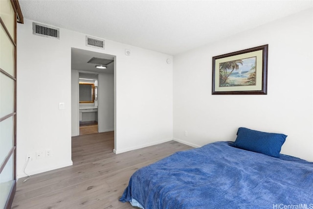 bedroom featuring visible vents, baseboards, and wood finished floors