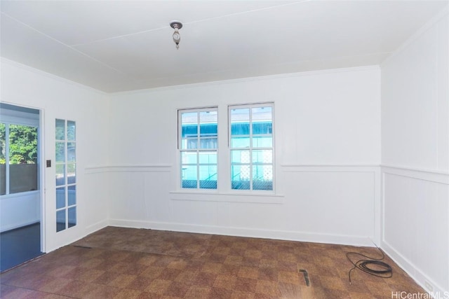 spare room featuring ornamental molding, a wealth of natural light, and a wainscoted wall