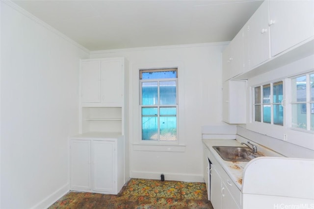 kitchen with baseboards, a sink, white cabinetry, and crown molding