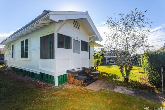 view of side of property featuring entry steps and a lawn