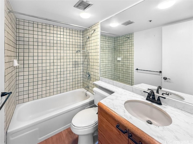 bathroom with toilet, wood finished floors, vanity, visible vents, and tub / shower combination