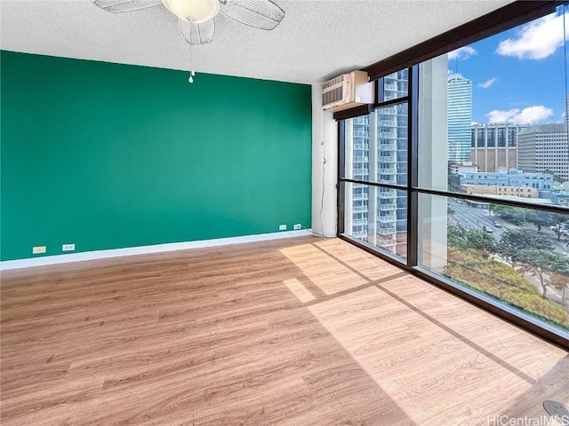 spare room featuring a city view, expansive windows, a textured ceiling, wood finished floors, and baseboards