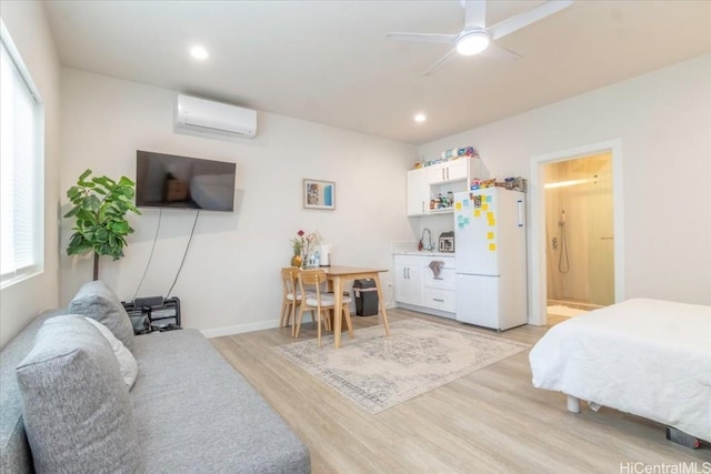 bedroom featuring recessed lighting, baseboards, light wood-style floors, freestanding refrigerator, and a wall mounted air conditioner