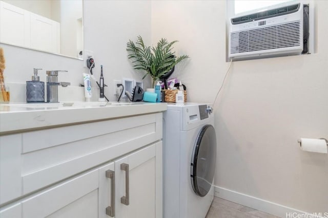 washroom with a wall unit AC, washer / clothes dryer, cabinet space, a sink, and baseboards