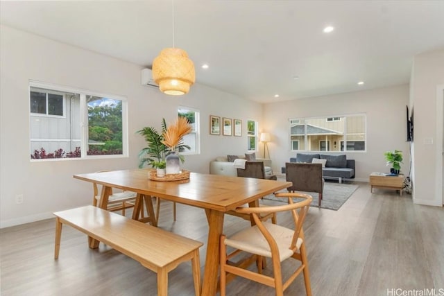 dining area with a wall unit AC, light wood-style flooring, baseboards, and recessed lighting