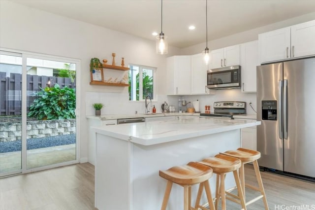 kitchen with white cabinets, decorative backsplash, a kitchen island, a kitchen breakfast bar, and stainless steel appliances