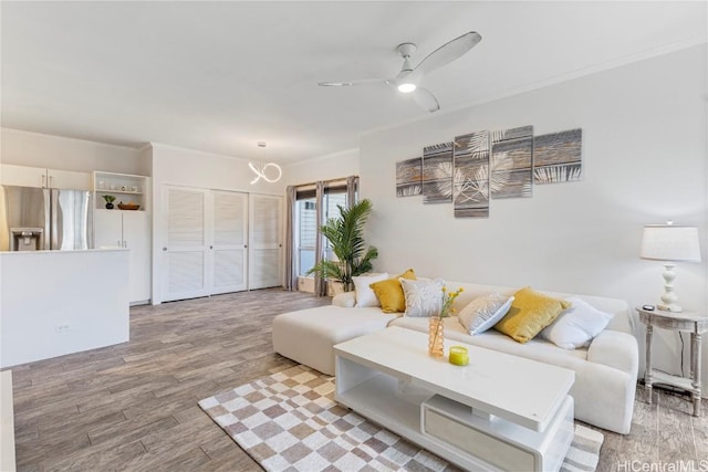 living room with crown molding, ceiling fan, and wood finished floors