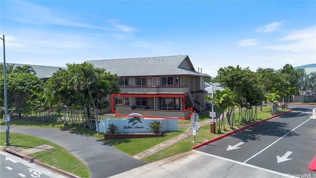 view of front of property featuring a balcony, a front lawn, and fence