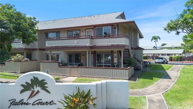 exterior space featuring a porch, a balcony, a front lawn, and a fenced front yard