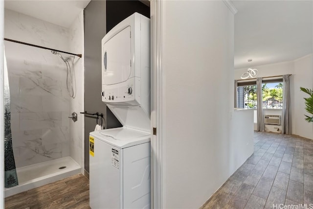 washroom featuring laundry area, stacked washing maching and dryer, and wood finish floors