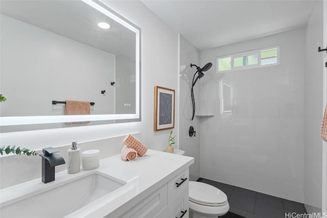 bathroom featuring a tile shower, vanity, toilet, and tile patterned floors