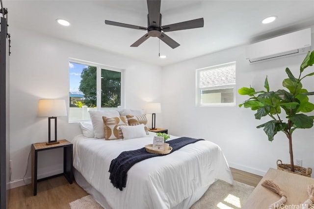 bedroom featuring recessed lighting, wood finished floors, a ceiling fan, baseboards, and a wall mounted AC