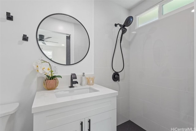 full bath featuring toilet, tiled shower, and vanity