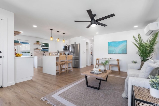 living area with light wood finished floors, a wall mounted AC, a ceiling fan, and recessed lighting