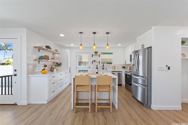 kitchen with light countertops, open shelves, decorative backsplash, light wood finished floors, and appliances with stainless steel finishes