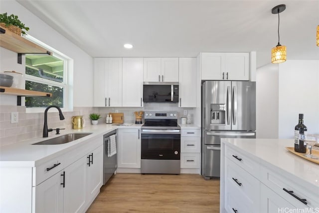 kitchen featuring appliances with stainless steel finishes, white cabinets, a sink, and tasteful backsplash