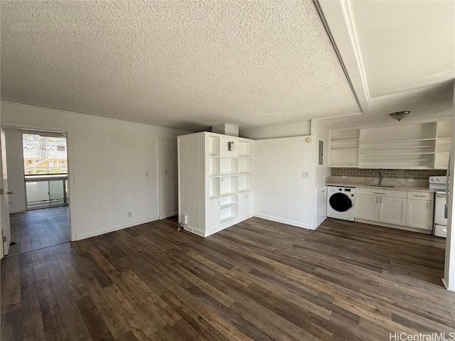 unfurnished living room with washer / clothes dryer, dark wood-type flooring, a sink, a textured ceiling, and baseboards