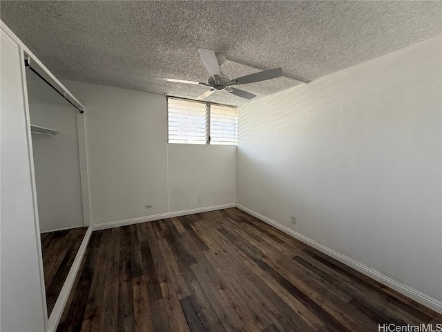 unfurnished bedroom featuring dark wood-style floors, a ceiling fan, baseboards, and a textured ceiling