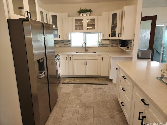 kitchen featuring light countertops, appliances with stainless steel finishes, a sink, and tasteful backsplash