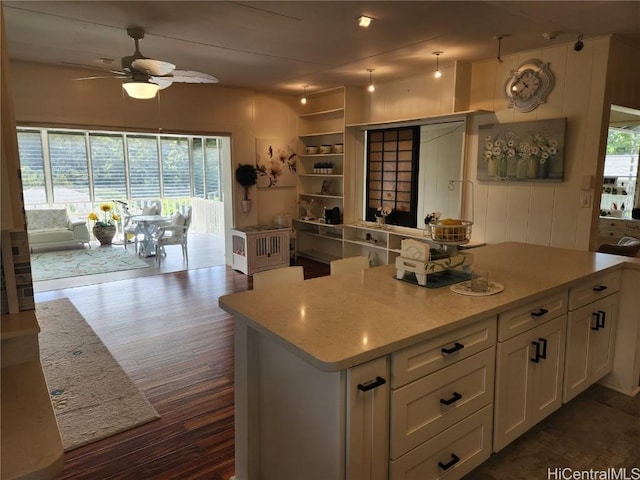 kitchen featuring white cabinets, dark wood-style floors, ceiling fan, a kitchen island, and light countertops