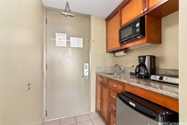 kitchen with black microwave, stainless steel dishwasher, brown cabinetry, and a sink