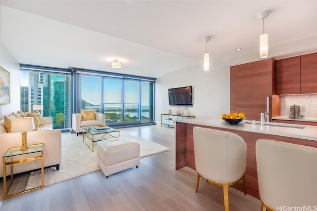 kitchen with light wood-style flooring, modern cabinets, open floor plan, hanging light fixtures, and expansive windows