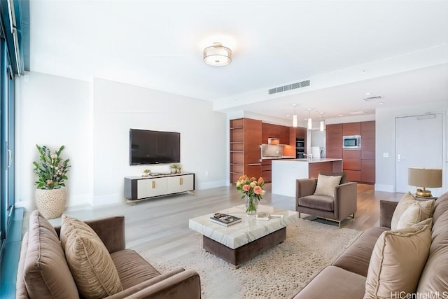 living room featuring light wood-style flooring, visible vents, and baseboards