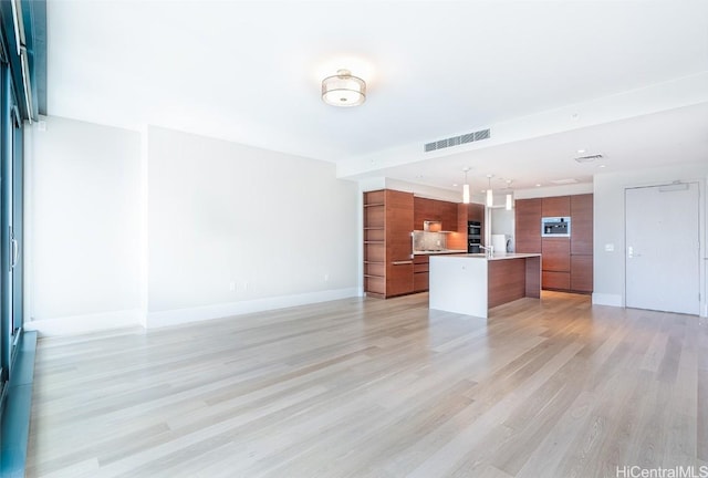 unfurnished living room with light wood finished floors, baseboards, and visible vents