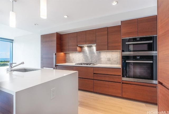 kitchen with double wall oven, light countertops, modern cabinets, and a sink