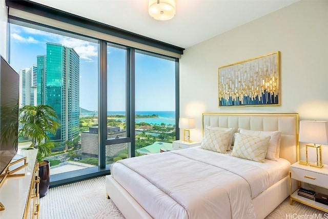 bedroom featuring a water view, multiple windows, floor to ceiling windows, and a city view