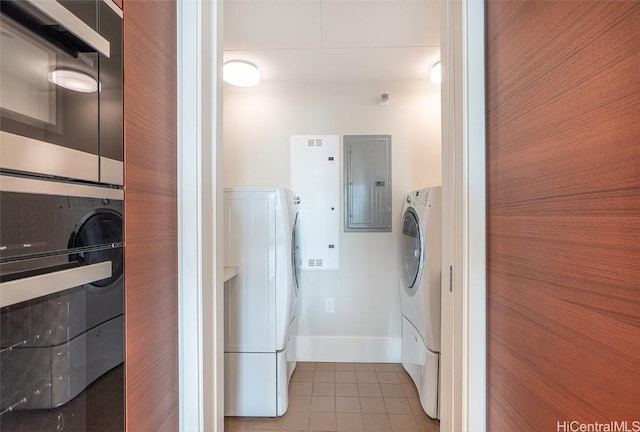 laundry room featuring baseboards, electric panel, washer / dryer, and tile patterned floors