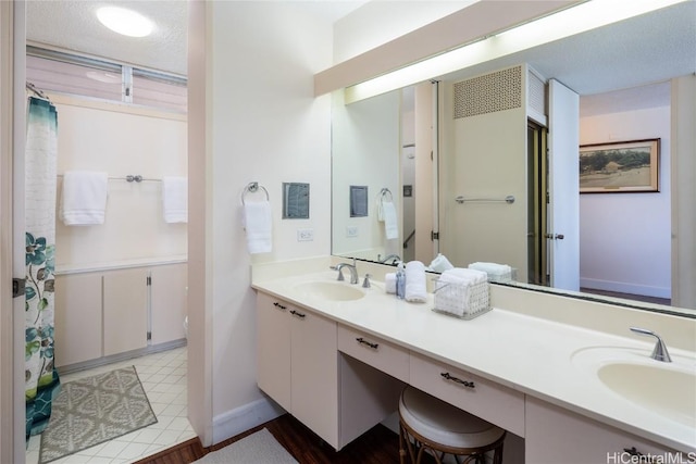 full bathroom with a sink, a textured ceiling, and double vanity