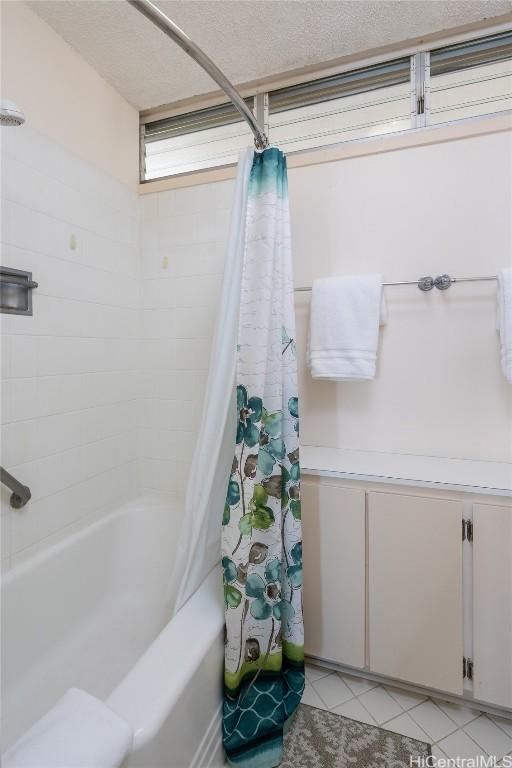 bathroom with a textured ceiling, tile patterned flooring, and shower / tub combo with curtain