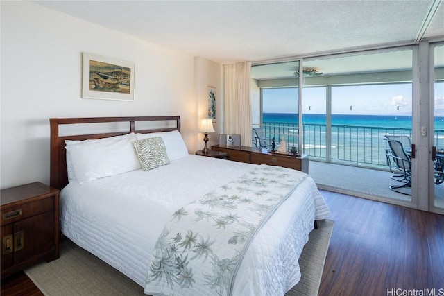 bedroom with a water view, access to outside, a wall of windows, and wood finished floors