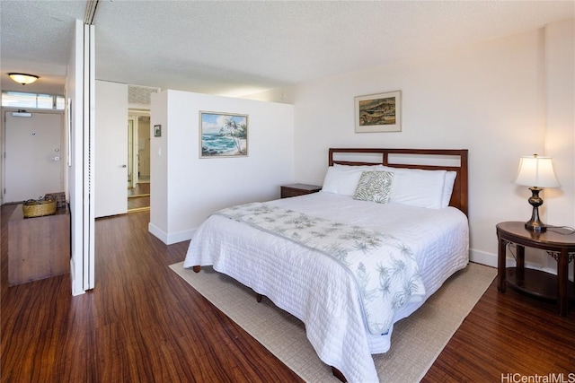 bedroom with a textured ceiling, baseboards, and wood finished floors