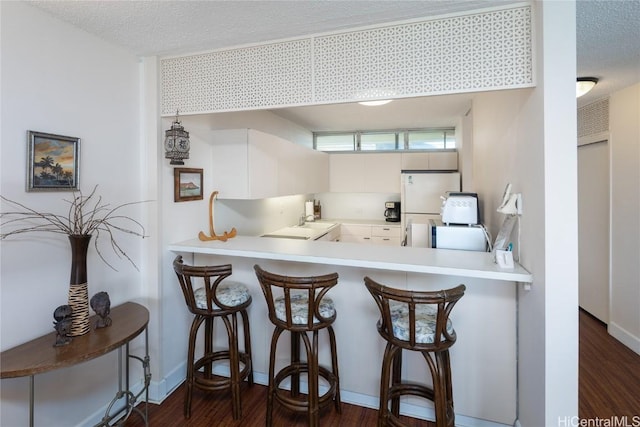 kitchen featuring dark wood-type flooring, freestanding refrigerator, a sink, and a textured ceiling